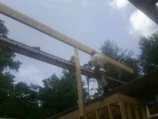Carpenter setting a ridge beam over a new addition frame — Ice Dam Removal by Roofing Brothers in Armonk