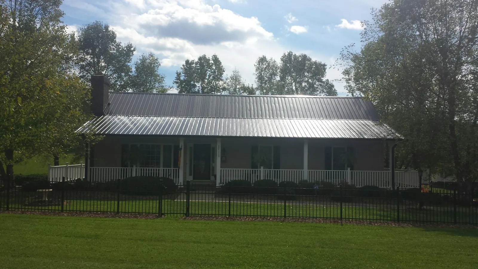 Gray metal roof on a brick ranch with a full width front porch — Gutter Guard Installation work by our crew in Armonk