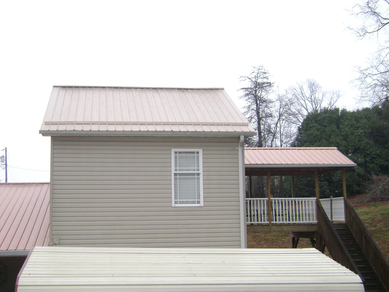 Tan metal roofs on a two story addition and attached porch, from a Roof Replacement job in Armonk