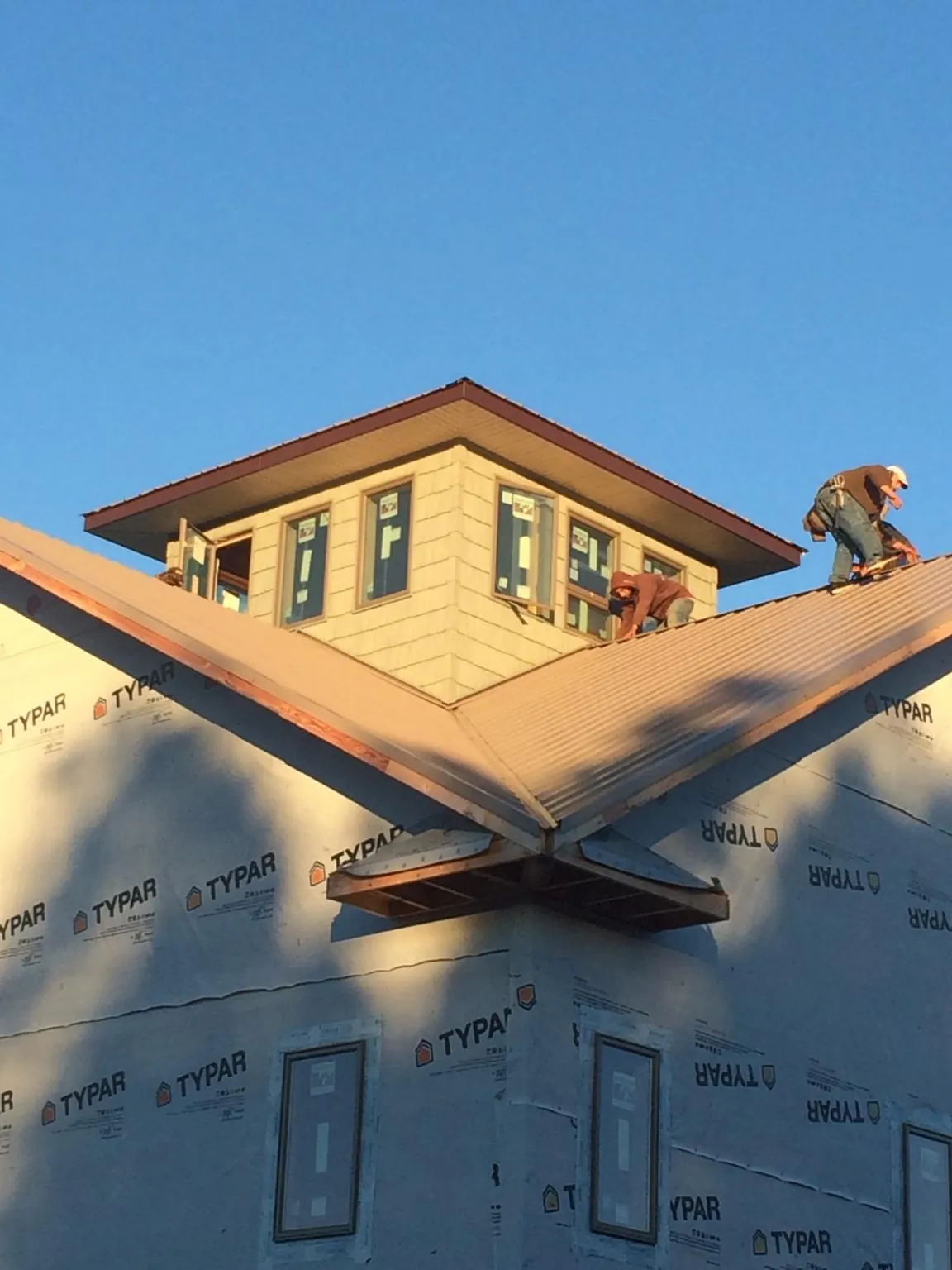 Roofers working around a rooftop cupola on a new metal roof at sunset — Roof Waterproofing in Armonk by Roofing Brothers